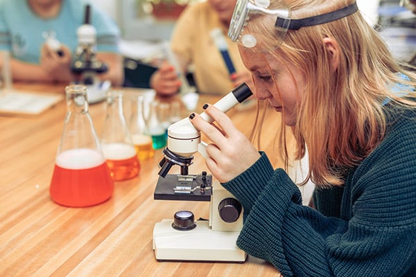 A teenage girl looks through a microscope while attending a residential anxiety treatment center | Discovery Ranch South - a residential treatment center for adolescent girls and teens assigned female at birth