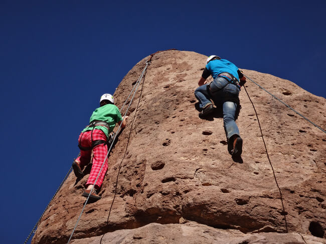 Teens climb a rock wall while participating in Rock Climbing Therapy at Discovery Ranch South, a residential treatment center for teenage girls and adolescents assigned female at birth