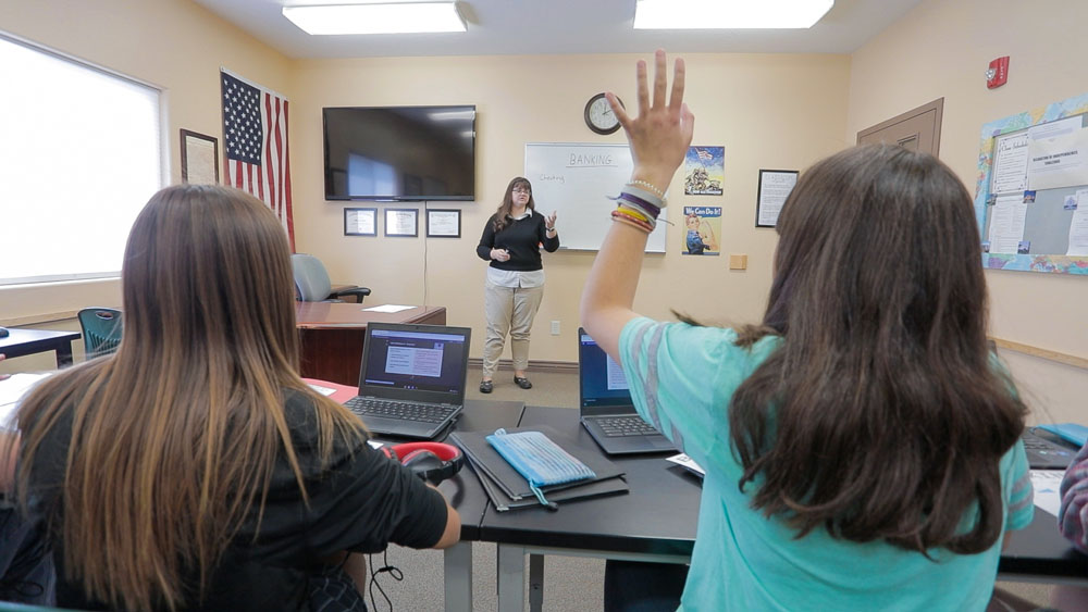 A student raises her hand while attending the therapeutic school at Discovery Ranch South, residential treatment for girls and teens assigned female at birth
