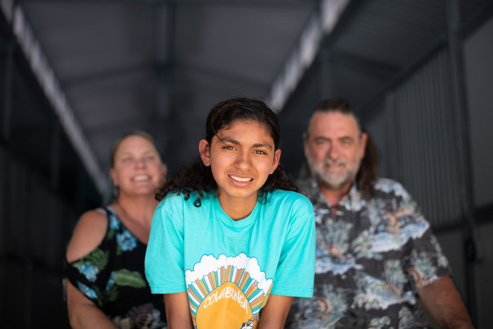 A family poses and smiles at the camera while attending residential treatment for teens at Discovery Ranch South, a Treatment Center for Girls and Teens Assigned Female at Birth