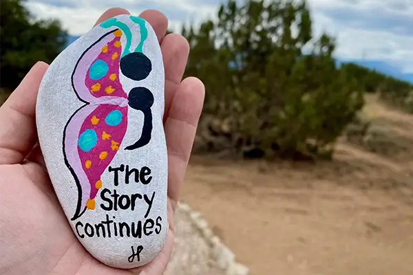 A student holding a rock with the words, "The Story continues" as a way to illustrate the healing power of EMDR for teens struggling with trauma and PTSD | Discovery Ranch South, a residential treatment center for girls and teens assigned female at birth